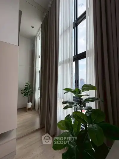 Elegant modern interior with tall windows and lush greenery, offering a serene and stylish living space.