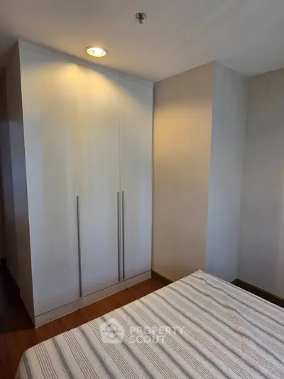 Modern bedroom with sleek wardrobe and cozy bed in stylish apartment.