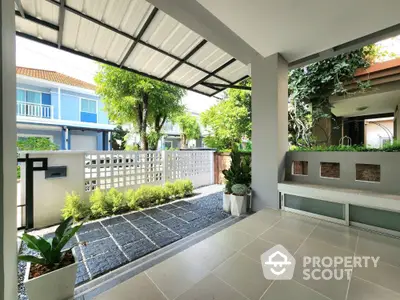 Charming modern home entrance with lush garden and covered patio, perfect for relaxation and outdoor enjoyment.