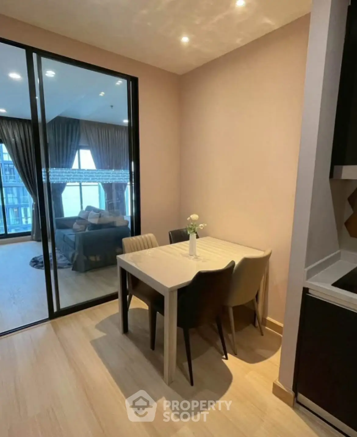 Modern dining area with glass doors leading to a cozy living room in a stylish apartment.