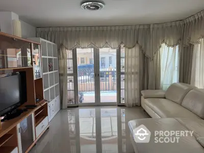 Spacious living room with elegant curtains and modern furniture, featuring a large balcony view.