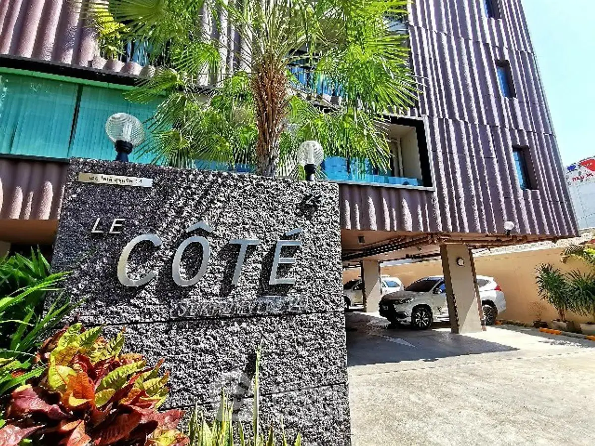 Modern apartment building entrance with parking and lush greenery
