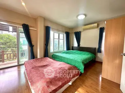 Spacious bedroom with large windows and balcony access, featuring wooden flooring and modern decor.