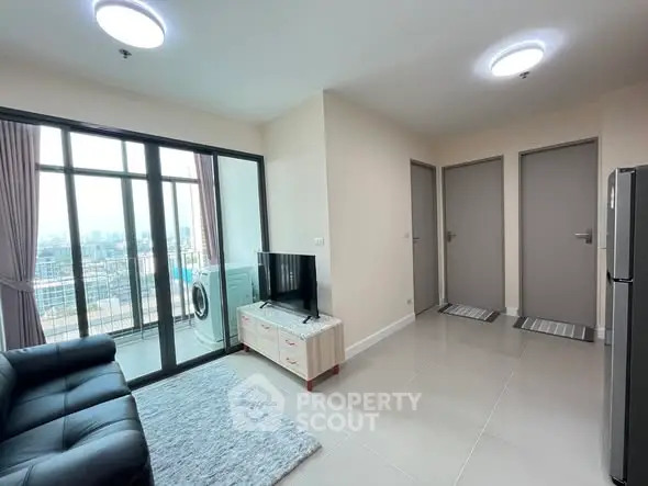 Modern living room with balcony view and sleek furniture in high-rise apartment.