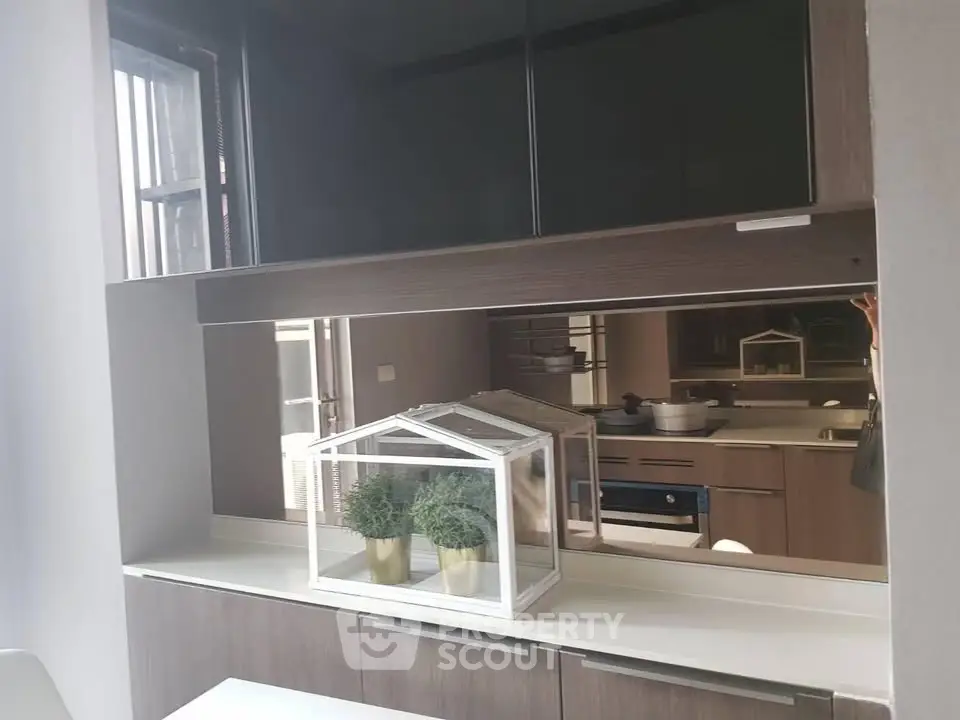 Modern kitchen with sleek cabinetry and built-in oven, featuring stylish decor.