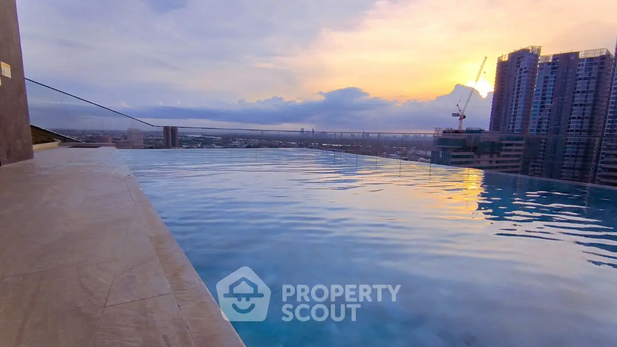 Stunning rooftop infinity pool with breathtaking city skyline view at sunset.