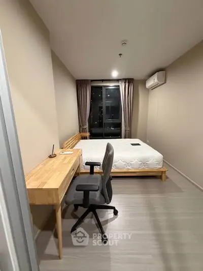 Modern bedroom with minimalist design, featuring a comfortable bed, wooden desk, and sleek chair.