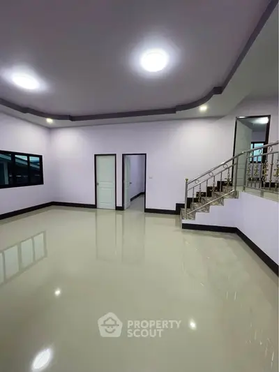 Spacious empty living room with glossy floors and elegant staircase, perfect for customization.