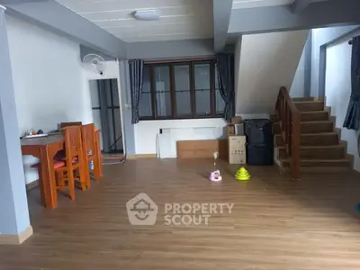 Spacious open-plan living area with wooden flooring and staircase