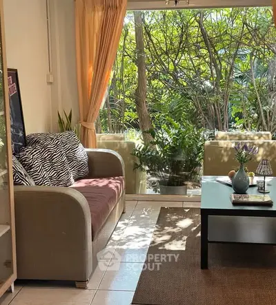 Cozy living room with large window and garden view, featuring a stylish sofa and coffee table.