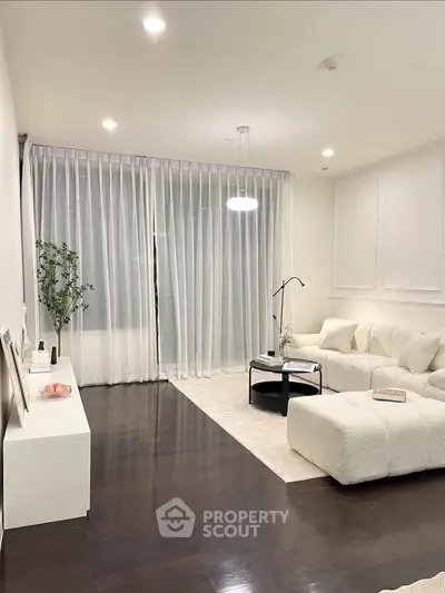 Elegant living room with modern white furniture and floor-to-ceiling curtains, perfect for cozy gatherings.