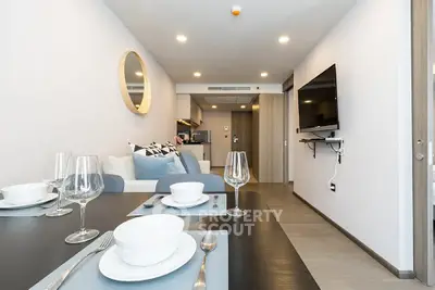Modern open-plan living room with dining area and wall-mounted TV in a stylish apartment.