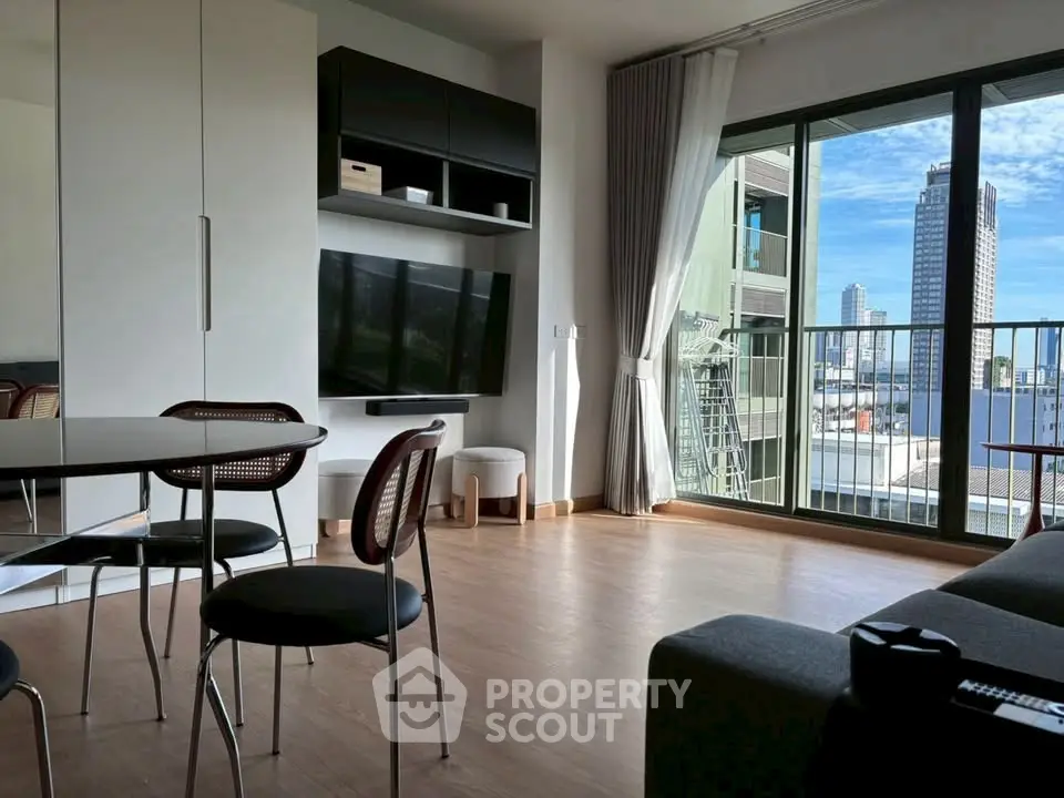 Modern living room with balcony and city view, featuring sleek furniture and natural light.