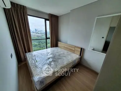 Modern bedroom with large window offering stunning city and park views, featuring a new mattress and sleek design.