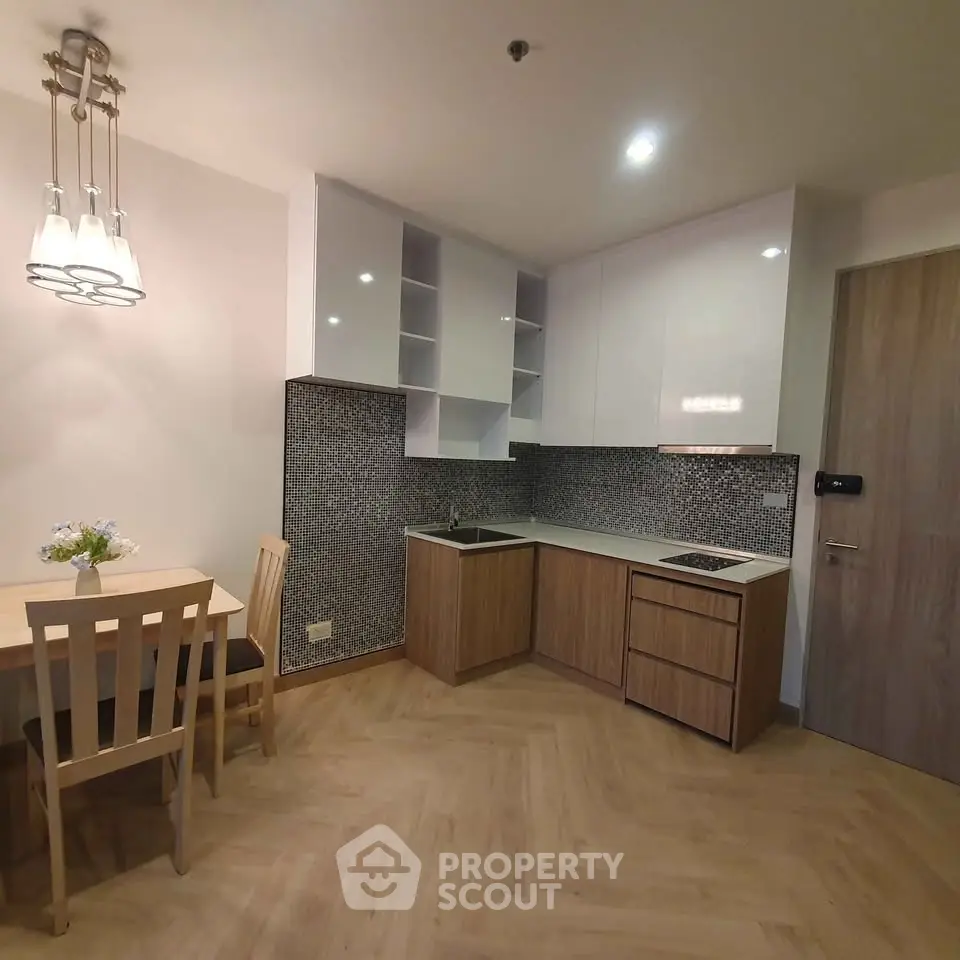 Modern kitchen with sleek cabinetry and dining area in stylish apartment.