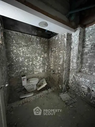 Unfinished bathroom with exposed concrete walls and toilet installation.