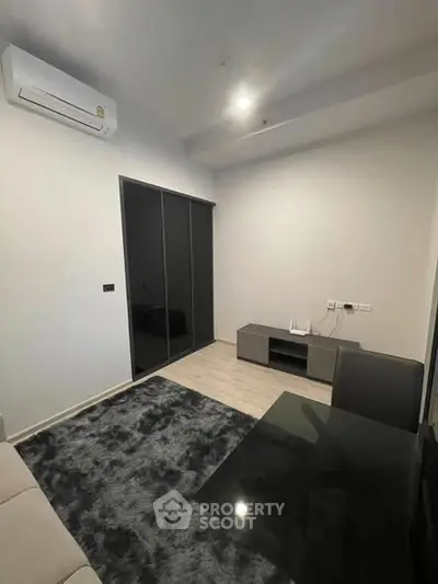 Modern living room with sleek furniture and air conditioning unit, featuring a stylish carpet and minimalist decor.