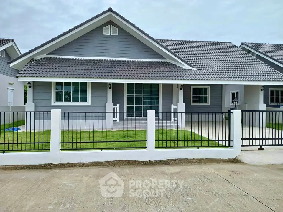 Charming single-story gray house with modern design and fenced front yard.