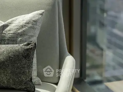 Elegant modern chair with textured cushions by a large window with city view.