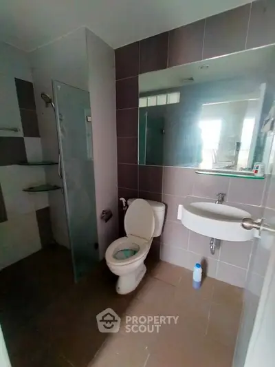 Modern bathroom with glass shower and sleek fixtures in contemporary apartment.