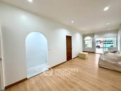 Spacious modern living room with wooden flooring and large windows for natural light.