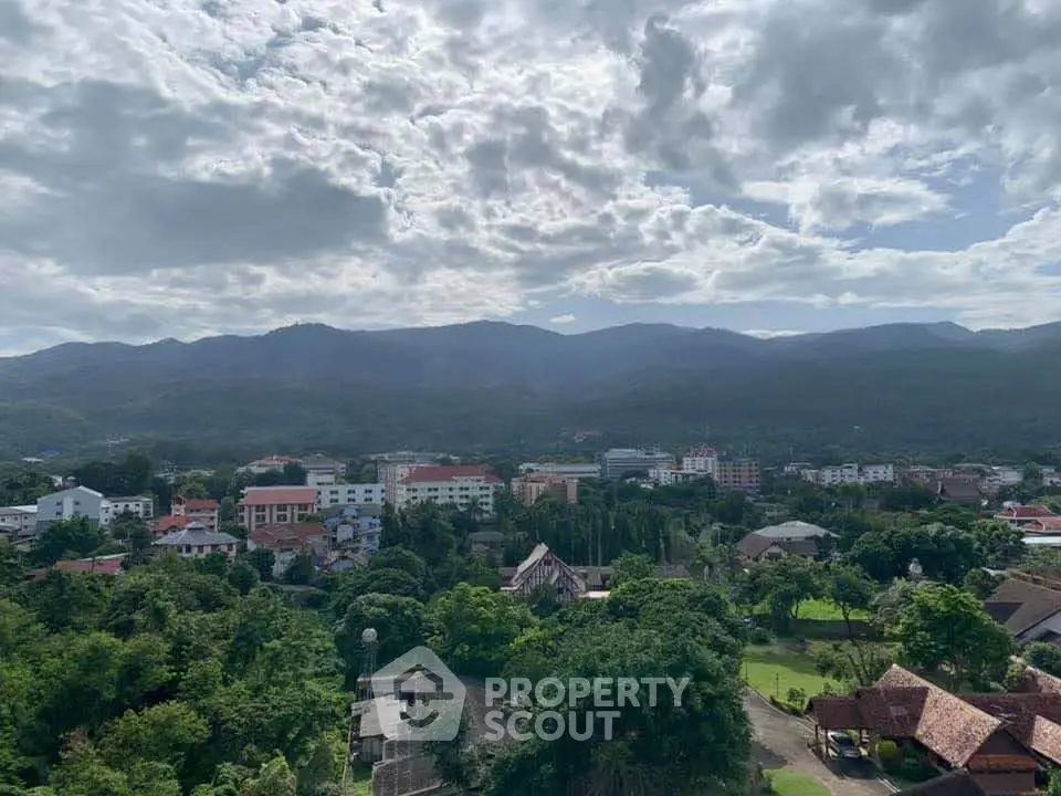 Scenic view of lush green landscape and cityscape with mountains in the background.