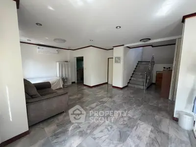 Spacious living room with modern staircase and elegant marble flooring.
