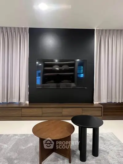 Modern living room with sleek TV setup and stylish round tables