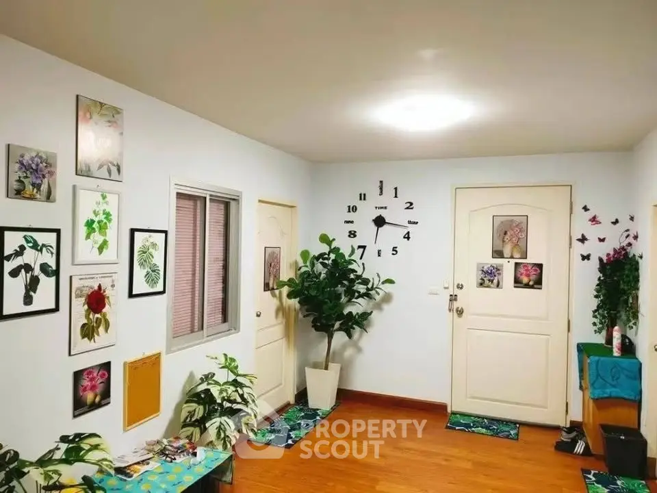 Charming interior hallway with vibrant decor and wooden flooring, featuring wall art and lush plants.