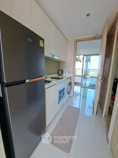 Modern kitchen with sleek appliances and open layout, featuring a washing machine and refrigerator.