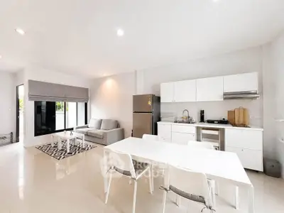 Modern open-plan kitchen and living room with sleek white furniture and natural light.