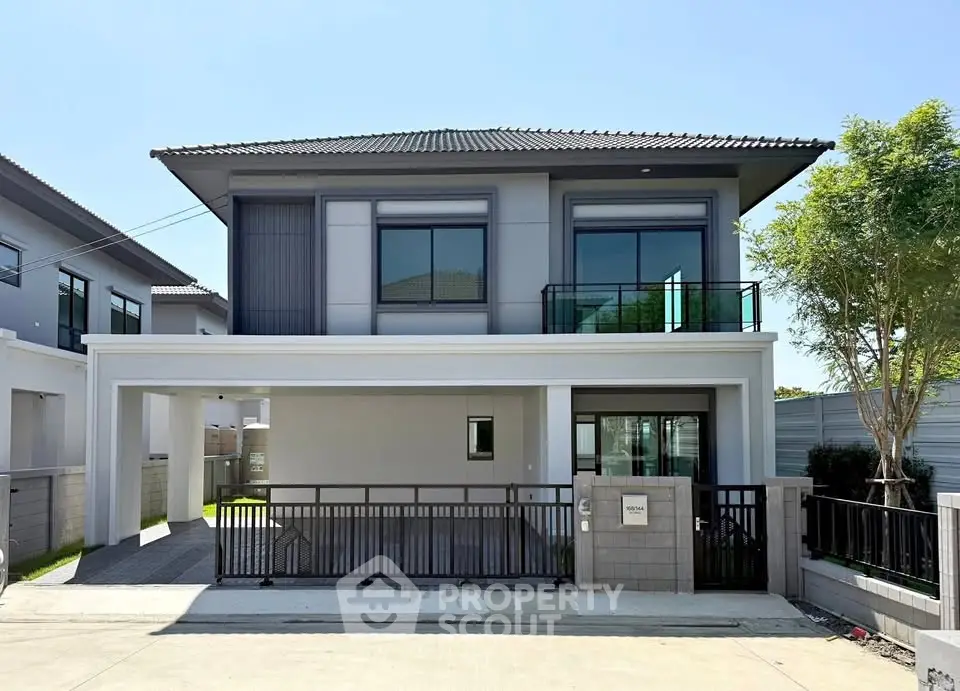 Modern two-story house with sleek design and gated driveway in a suburban neighborhood.