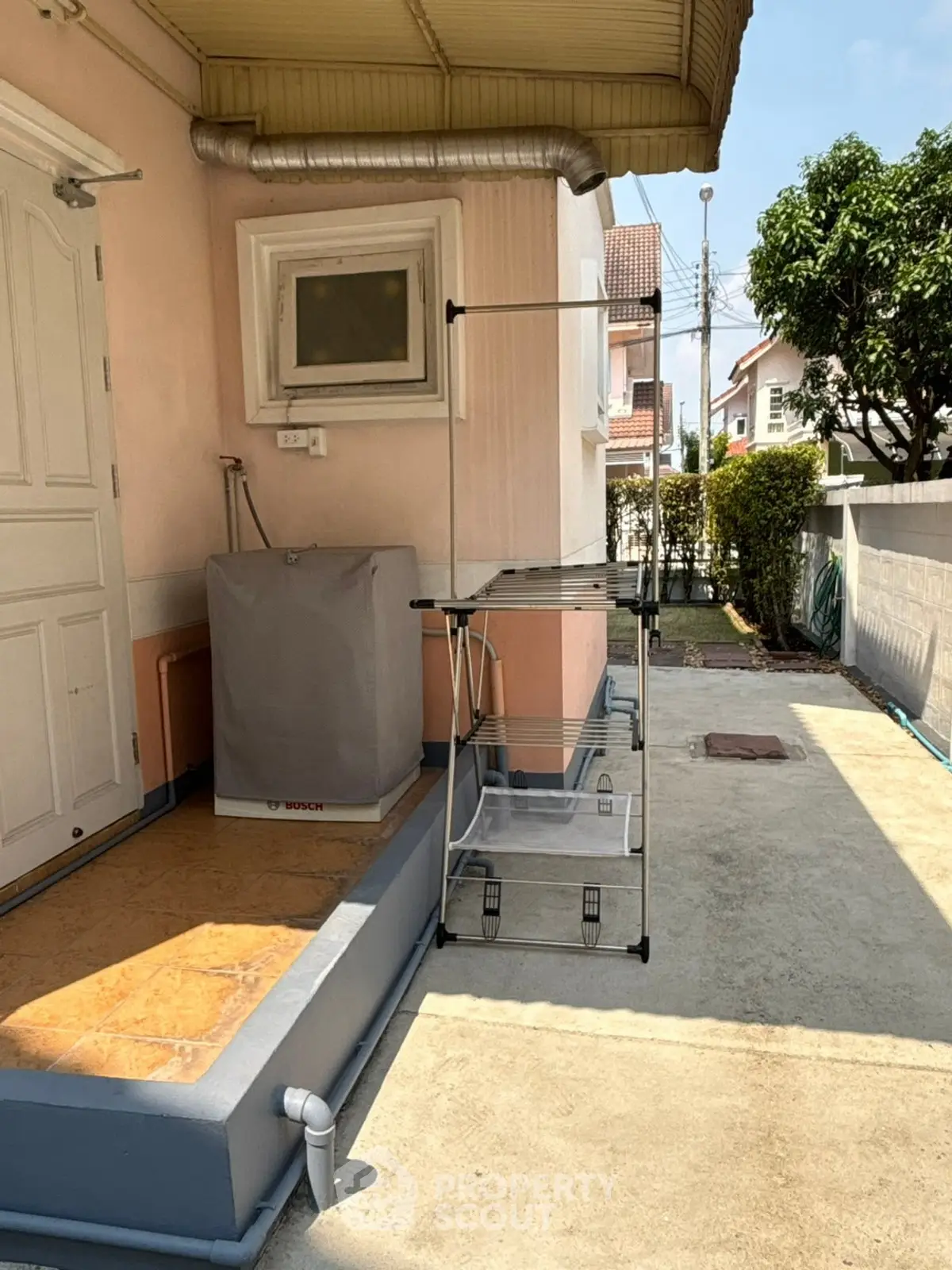 Charming residential exterior with laundry area and Bosch washing machine, perfect for convenient outdoor chores.