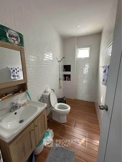 Modern bathroom with white tiles, wooden floor, and sleek fixtures.