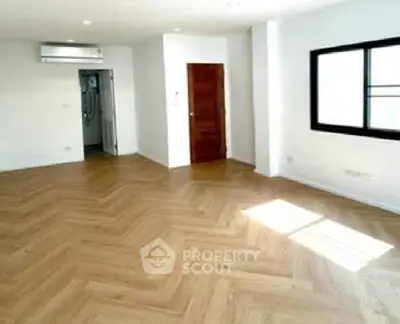 Spacious empty room with wooden flooring and natural light