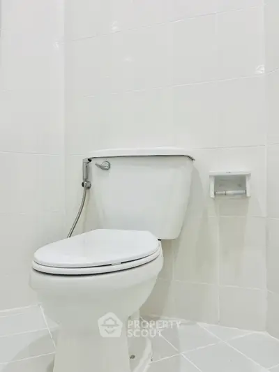 Modern white bathroom with sleek toilet and tiled walls.