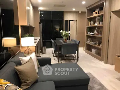 Modern living room with stylish decor and open dining area, featuring cozy seating and elegant lighting.