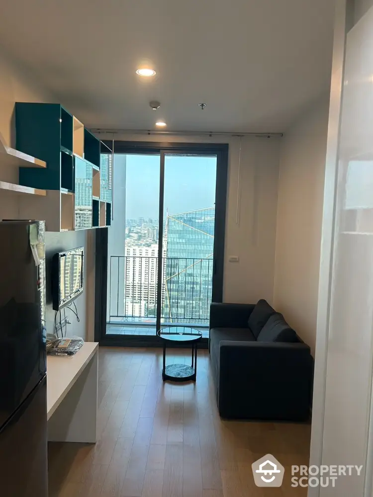 Modern living room with city view and balcony access in high-rise apartment.