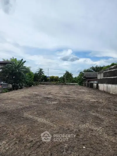 Spacious open land with potential for development, surrounded by lush greenery and clear skies.