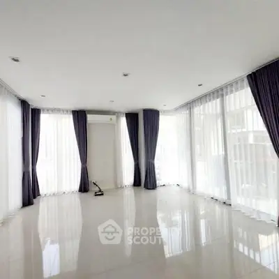 Spacious empty living room with large windows and elegant curtains