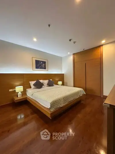 Spacious modern bedroom with wooden flooring and ambient lighting