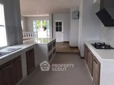 Modern kitchen with open layout and gas stove, featuring sleek countertops and ample natural light.