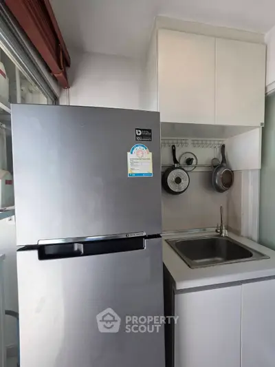 Compact kitchen with modern fridge and sink in cozy apartment.