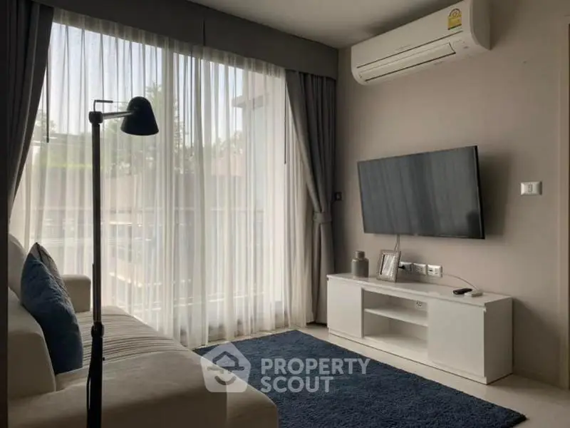 Modern living room with large window, stylish sofa, and wall-mounted TV in a cozy apartment.