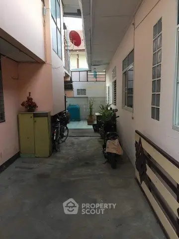 Narrow alleyway with motorbikes and plants in residential building exterior