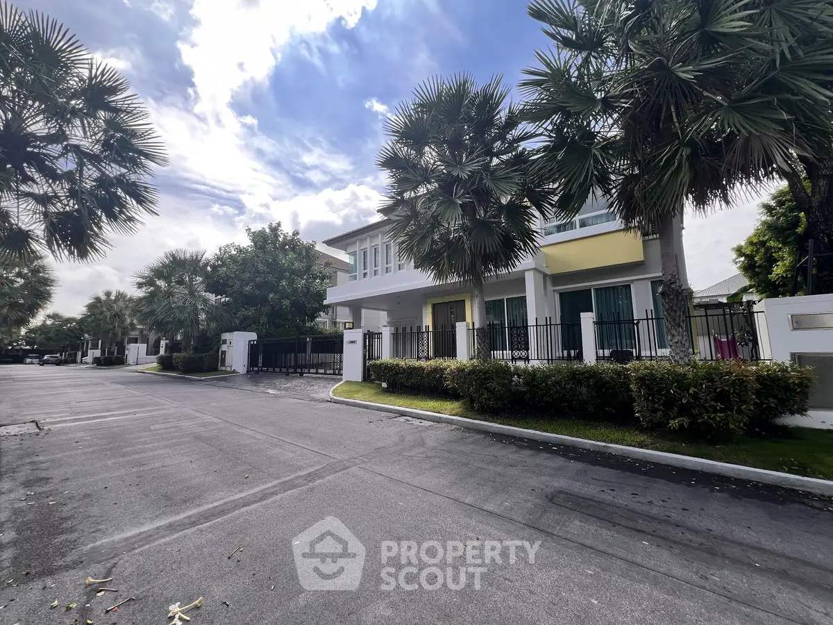 Modern two-story house with palm trees and spacious driveway in a serene neighborhood.