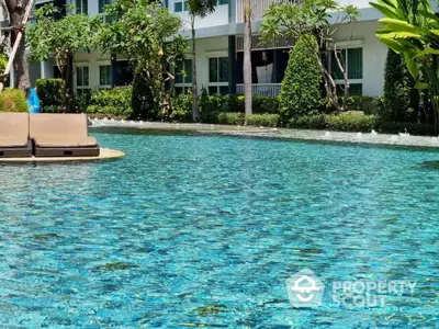 Luxurious residential pool with lush greenery and modern building backdrop.