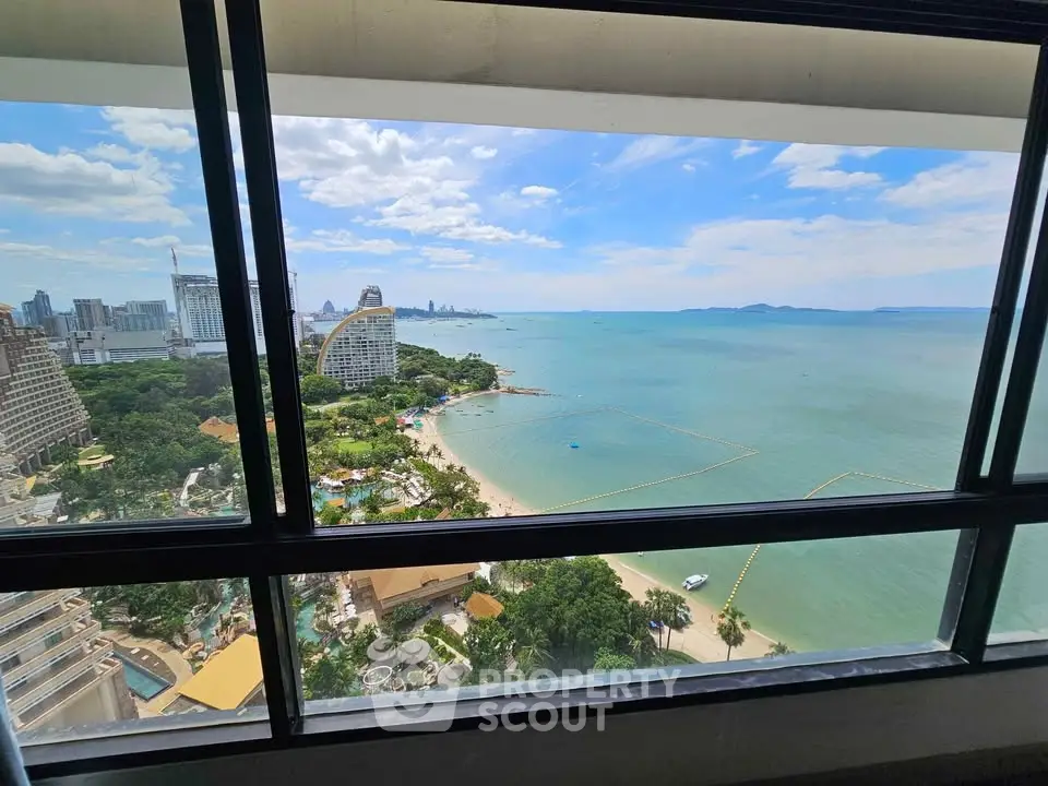 Stunning high-rise view of ocean and city skyline from a modern apartment window.