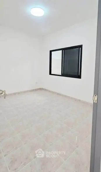 Spacious empty room with tiled flooring and large window
