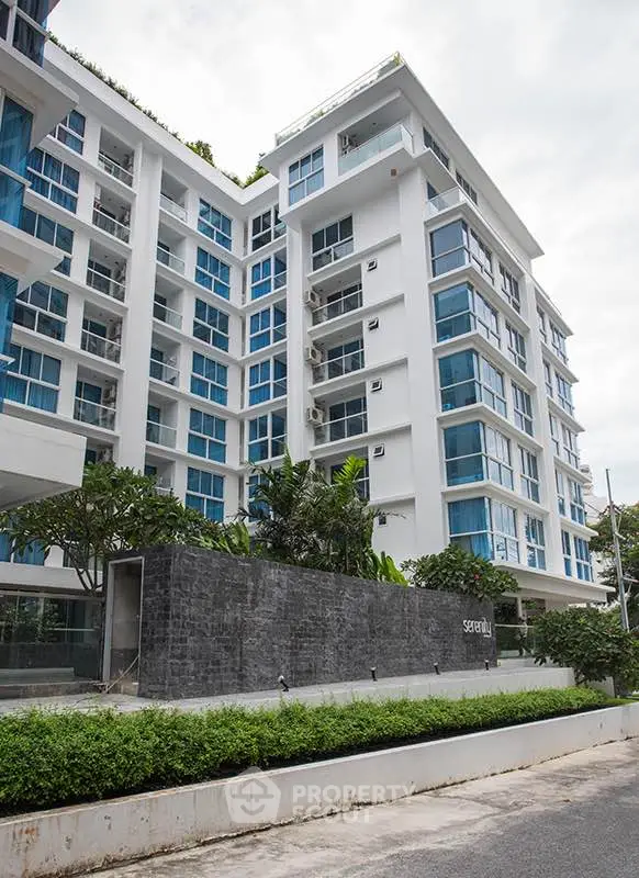 Modern multi-story residential building with lush greenery and sleek design.